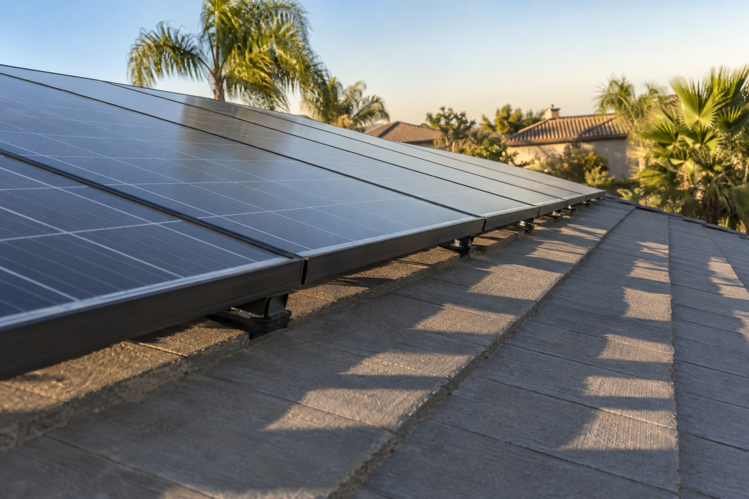 Solar panels sitting on rails just above new concrete roof tile in late afternoon light